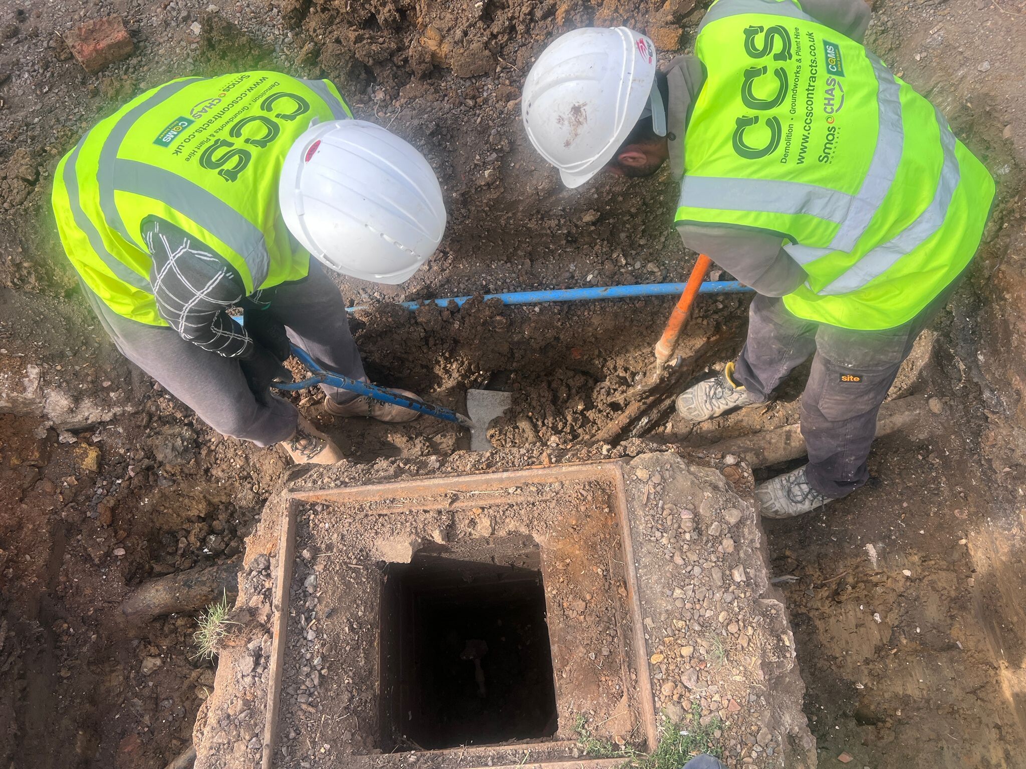 Two CCS Contractors Ltd groundworks operatives working together in PPE on a construction site.